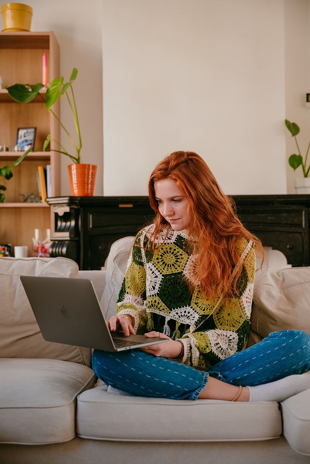 Yasmine, the founder of Learn Dutch with Yas, sitting in a sofa with a laptop on her knee