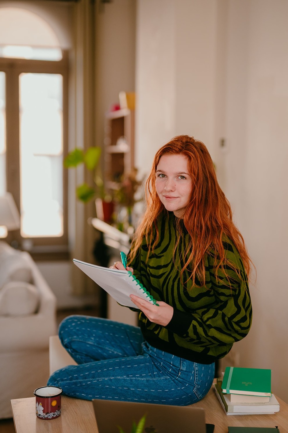 Yasmine, the founder of Learn Dutch with Yas, smiling at the camera while taking notes in a notepad