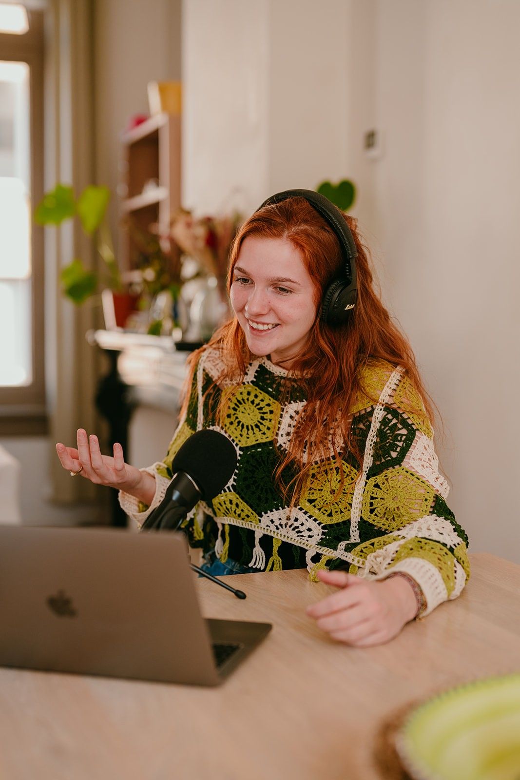 Yasmine from Learn Dutch with Yas sitting behind a desk while recording a podcast