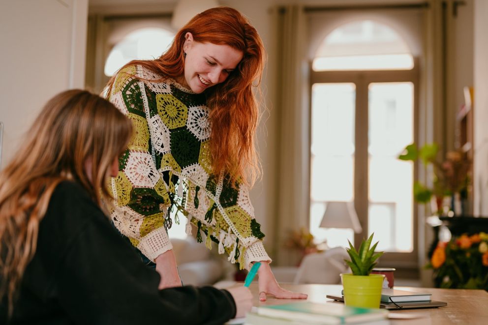 Yasmine, the founder of Learn Dutch with Yas, teaching a person Dutch who is writing on a notepad