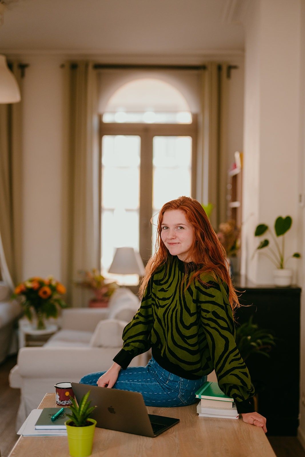 Yasmine, the founder of Learn Dutch With Yas, sitting on a desk, smiling at the camera