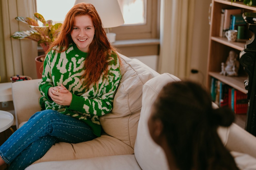 Yasmine, the founder of Learn Dutch with Yas, holding a conversation with another person on a couch